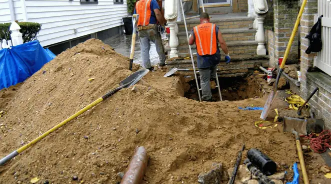 Contractors performing foundation protection and exterior drainage excavation near residential home steps in Stamford, CT